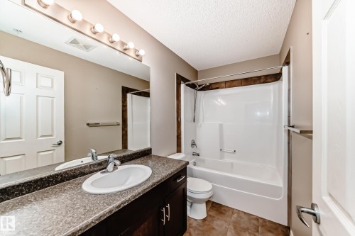 Bathroom featuring a vanity with a large mirror, a white sink with chrome fixtures, and a shower-bathtub combination with brown tiled surround - 208 2204 44 Ave, Edmonton, AB - Indoor Photo Showing Bathroom
