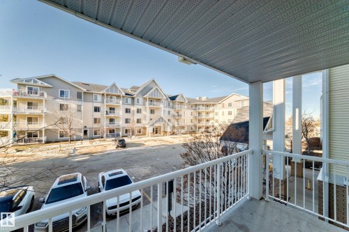 The property features a private balcony with white railings, offering views of the surrounding apartment buildings and parking area - 208 2204 44 Ave, Edmonton, AB - Outdoor With Balcony