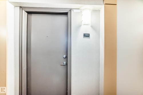The property features a private entrance with a gray door and a modern wall-mounted light fixture - 208 2204 44 Ave, Edmonton, AB - Indoor