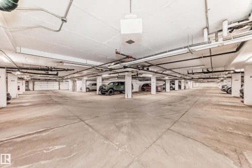 The property features a spacious underground parking garage with concrete floors and a fire extinguisher visible on a pillar - 208 2204 44 Ave, Edmonton, AB - Indoor Photo Showing Garage