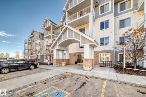 The property features a multi-story building with a light-colored exterior and brick accents, presenting a welcoming entrance with an arched portico - 208 2204 44 Ave, Edmonton, AB - Outdoor With Balcony With Facade