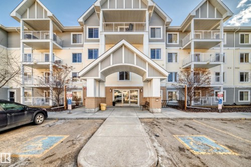 The property features a multi-story building with balconies, a covered entrance with an arched portico, and a paved walkway leading to the entrance - 208 2204 44 Ave, Edmonton, AB - Outdoor With Balcony With Facade