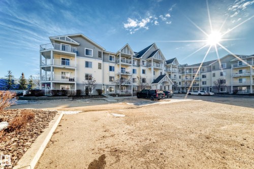 The property is a multi-story building featuring light-colored siding and grey gables - 208 2204 44 Ave, Edmonton, AB - Outdoor With Balcony With Facade