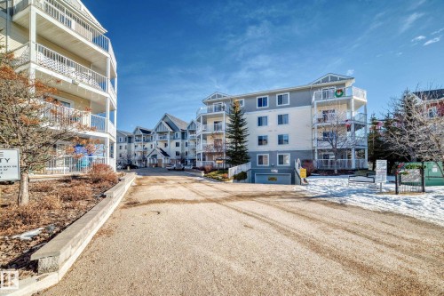 This property features a multi-story building with balconies, set against a clear blue sky - 208 2204 44 Ave, Edmonton, AB - Outdoor With Balcony With Facade