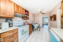 The kitchen features white tile flooring, wood cabinetry, and a white electric range - 