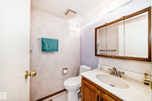 Bathroom featuring a single vanity with a white countertop and a wood-framed mirror cabinet - 11393 22 Avenue, Edmonton, AB - Indoor Photo Showing Bathroom