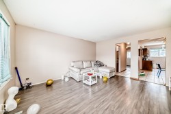 Living area featuring light-colored walls and wood-look flooring - 