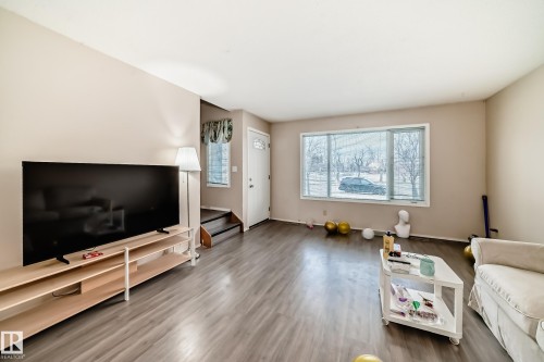 Spacious living area featuring light-toned walls, wood-look flooring, and a large window providing views of the outdoors - 11393 22 Avenue, Edmonton, AB - Indoor Photo Showing Living Room