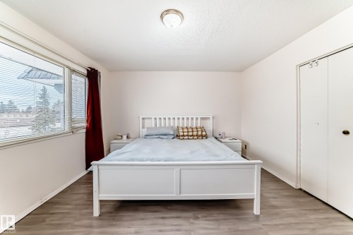 This room features light-colored walls, a ceiling-mounted light fixture, and wood-look flooring - 11393 22 Avenue, Edmonton, AB - Indoor Photo Showing Bedroom