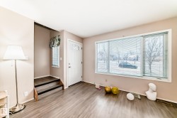 The property features durable flooring, a large window providing natural light, and a white entry door with decorative glass inserts - 