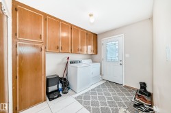 The laundry room features wood cabinetry providing storage, a white exterior door with decorative glass, and a white tile floor - 