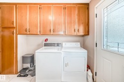 Convenient laundry area featuring wooden cabinetry, a white washer, and a white dryer - 