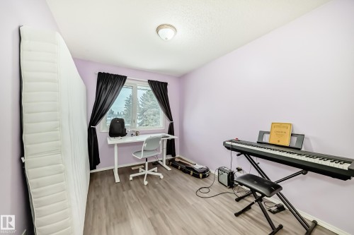 This room features light purple walls, wood-style flooring, and a window with dark curtains - 11393 22 Avenue, Edmonton, AB - Indoor
