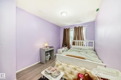 This room features light purple walls, a window with brown curtains, and a white bed frame - 