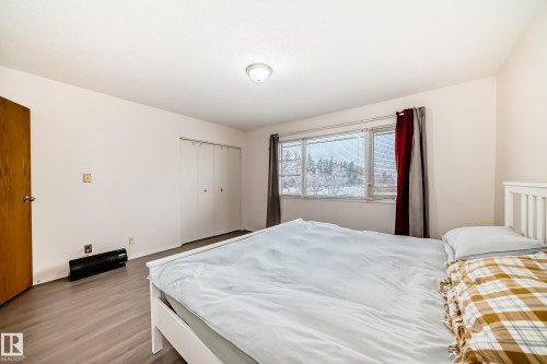 Room featuring light-toned walls, a window with views of trees, and a closet with bifold doors - 11393 22 Avenue, Edmonton, AB - Indoor Photo Showing Bedroom
