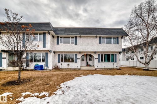 The property features a multi-level structure with a grey roof and white exterior, complemented by blue window shutters - 11393 22 Avenue, Edmonton, AB - Outdoor With Facade