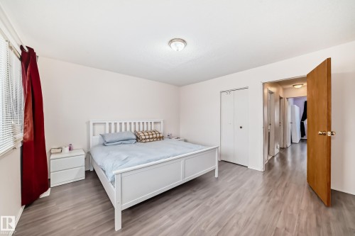 This room features light-toned flooring, white walls, and a window with blinds and red drapes - 11393 22 Avenue, Edmonton, AB - Indoor Photo Showing Bedroom