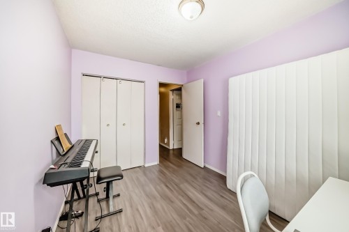 This room features light purple walls, wood-look flooring, and a ceiling light fixture - 11393 22 Avenue, Edmonton, AB - Indoor