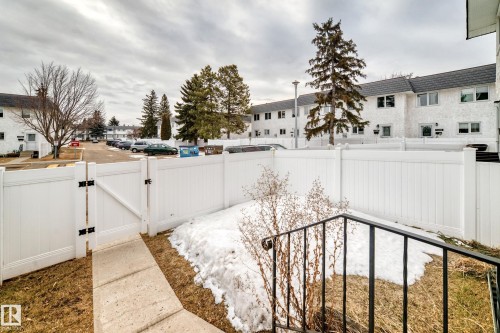 The property features a white fence with a gate, a concrete path, and visible exterior railing - 11393 22 Avenue, Edmonton, AB - Outdoor