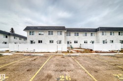 The property features a multi-unit building with a white exterior finish and dark sloped roofs - 