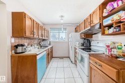 The kitchen features wood cabinetry, white tile flooring, and a window providing natural light - 