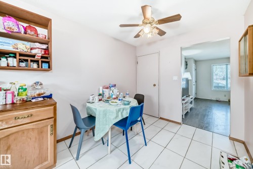 This dining area features white tiled flooring and a ceiling fan with integrated lighting - 11393 22 Avenue, Edmonton, AB - Indoor
