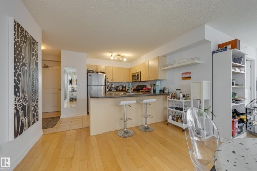 The property features an open-concept living area with light hardwood floors - 1007 10180 104 Street, Edmonton, AB - Indoor Photo Showing Kitchen