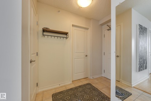 Entryway featuring light-colored tile flooring, a mounted coat rack, and a ceiling light fixture - 1007 10180 104 Street, Edmonton, AB - Indoor Photo Showing Other Room
