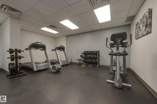 The property includes a fitness area with two treadmills, an elliptical machine, and a selection of free weights - 1007 10180 104 Street, Edmonton, AB - Indoor Photo Showing Gym Room