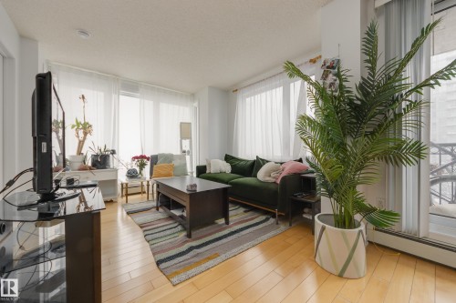 Bright living area featuring hardwood flooring and large windows with privacy sheers - 1007 10180 104 Street, Edmonton, AB - Indoor Photo Showing Living Room