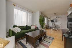 The living area features light hardwood flooring, large windows with sheer curtains, and recessed lighting - 