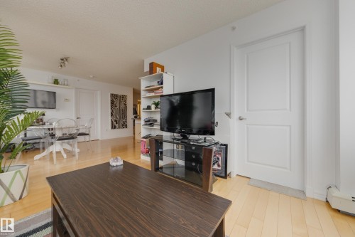 Living area featuring light wood flooring, white walls, and a modern white door - 1007 10180 104 Street, Edmonton, AB - Indoor Photo Showing Living Room