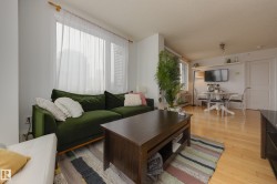 Living area featuring light wood flooring, a window with sheer white curtains, and a built-in shelf - 