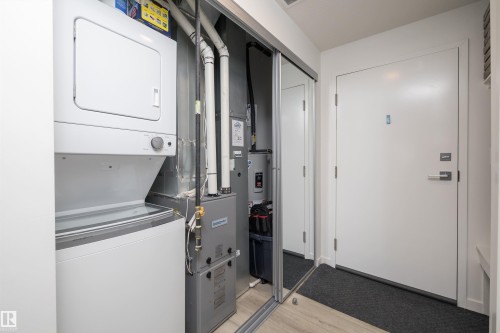 The property includes a stacked washer and dryer, located within a dedicated utility space - 101 860 Secord Blvd, Edmonton, AB - Indoor Photo Showing Laundry Room
