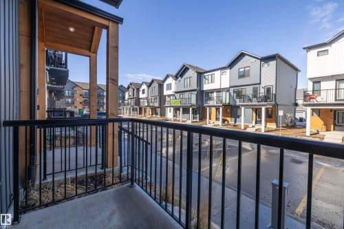 View from the property's balcony, featuring a concrete surface and black metal railings - 101 860 Secord Blvd, Edmonton, AB - Outdoor With Exterior