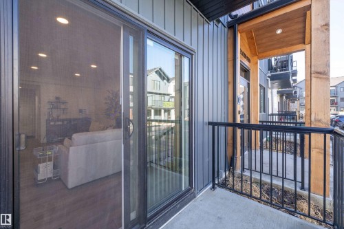 The property features an exterior balcony with black metal railings, a concrete floor, and wood structural elements - 101 860 Secord Blvd, Edmonton, AB - Outdoor With Exterior