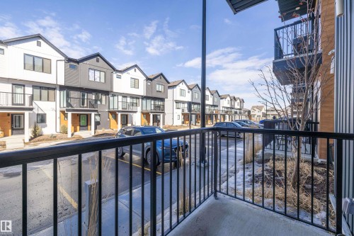 Balcony with black metal railings, overlooking the property's exterior and street - 101 860 Secord Blvd, Edmonton, AB - Outdoor With Exterior