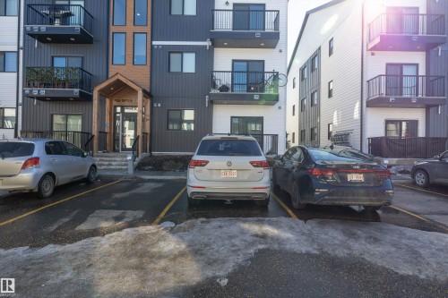 The property features a contemporary exterior with balconies, dark horizontal siding, and white vertical siding - 101 860 Secord Blvd, Edmonton, AB - Outdoor With Facade
