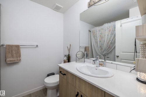 Bathroom featuring a light wood vanity with black hardware, quartz countertop - 101 860 Secord Blvd, Edmonton, AB - Indoor Photo Showing Bathroom