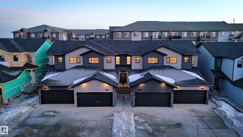The property features a dark gray shingled roof, light gray siding, and dark gray garage doors - 7694 174A Avenue, Edmonton, AB - Outdoor With Facade