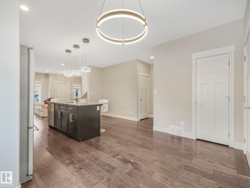 Open concept living area featuring dark wood flooring, a kitchen island with a light-colored countertop, and modern circular pendant lighting fixtures - 2 10319 120 Street, Edmonton, AB - Indoor Photo Showing Kitchen