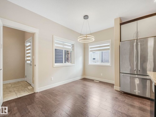 This dining area features hardwood floors and two windows with blinds - 2 10319 120 Street, Edmonton, AB - Indoor Photo Showing Other Room