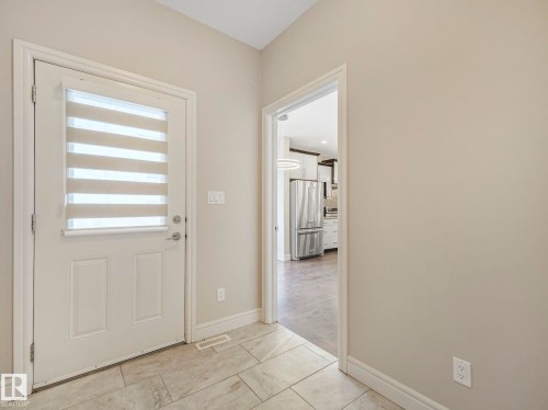 The entryway features tiled flooring, a paneled door with privacy blinds, and light-colored walls - 2 10319 120 Street, Edmonton, AB - Indoor Photo Showing Other Room