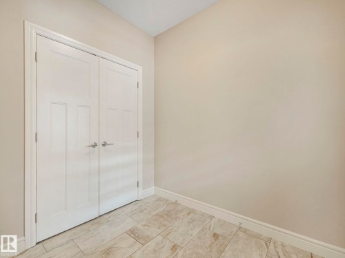 Room featuring neutral-toned walls, white trim, and light-colored tile flooring - 2 10319 120 Street, Edmonton, AB - Indoor Photo Showing Other Room