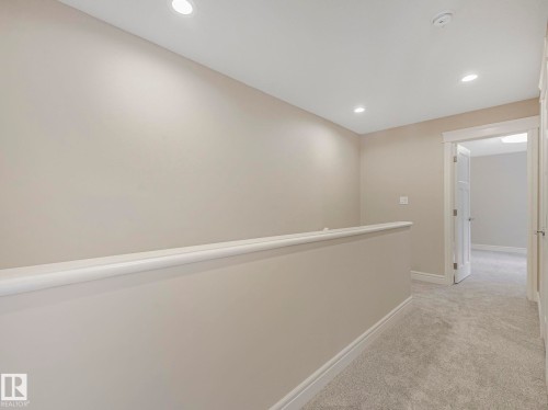 The property features neutral-toned walls, recessed lighting, and light grey carpeting, creating a bright and inviting atmosphere - 2 10319 120 Street, Edmonton, AB - Indoor Photo Showing Other Room