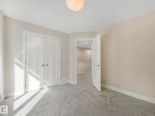 This room features light-colored walls and plush carpeting, creating a neutral and inviting atmosphere - 2 10319 120 Street, Edmonton, AB - Indoor Photo Showing Other Room