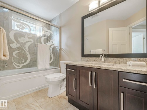 Bathroom featuring a dark wood vanity with a light-colored countertop, an undermount sink, and a framed mirror - 2 10319 120 Street, Edmonton, AB - Indoor Photo Showing Bathroom