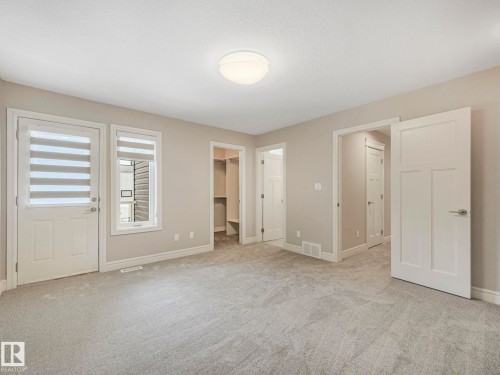 This spacious room features light-colored carpeting, neutral wall paint, and white trim throughout - 2 10319 120 Street, Edmonton, AB - Indoor Photo Showing Other Room
