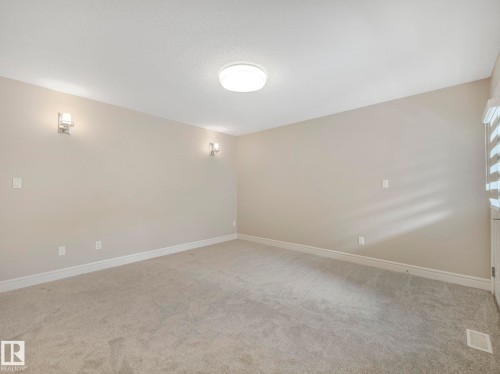 The room features light-colored carpeting, neutral walls, and a ceiling-mounted light fixture - 2 10319 120 Street, Edmonton, AB - Indoor Photo Showing Other Room