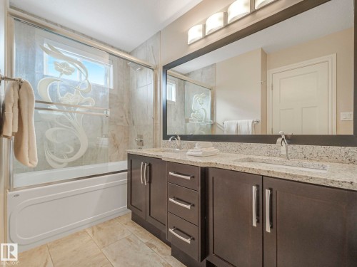 Bathroom with a dual vanity featuring granite countertops and dark wood cabinetry - 2 10319 120 Street, Edmonton, AB - Indoor Photo Showing Bathroom